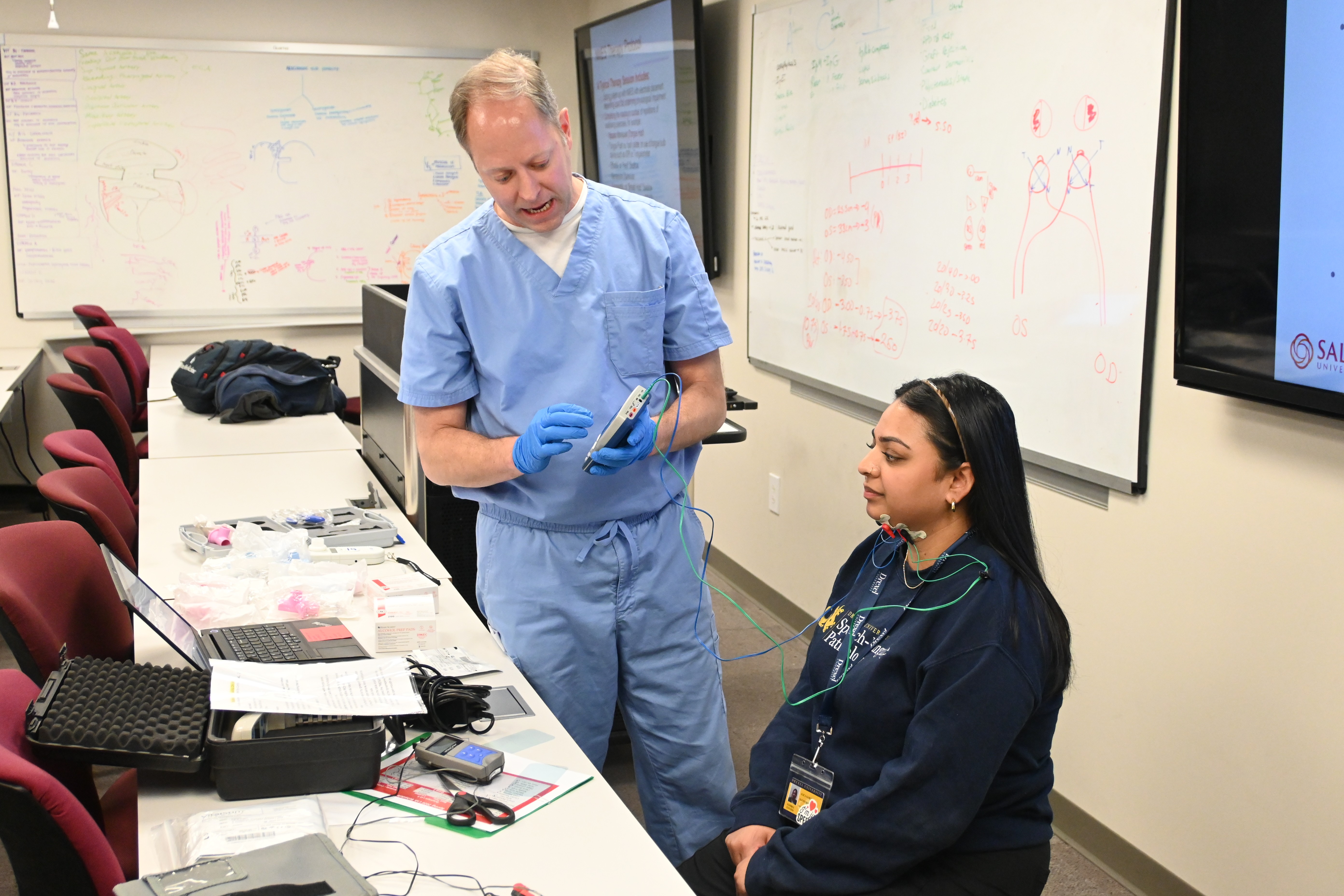 SLP instructor demonstrates with student in classroom