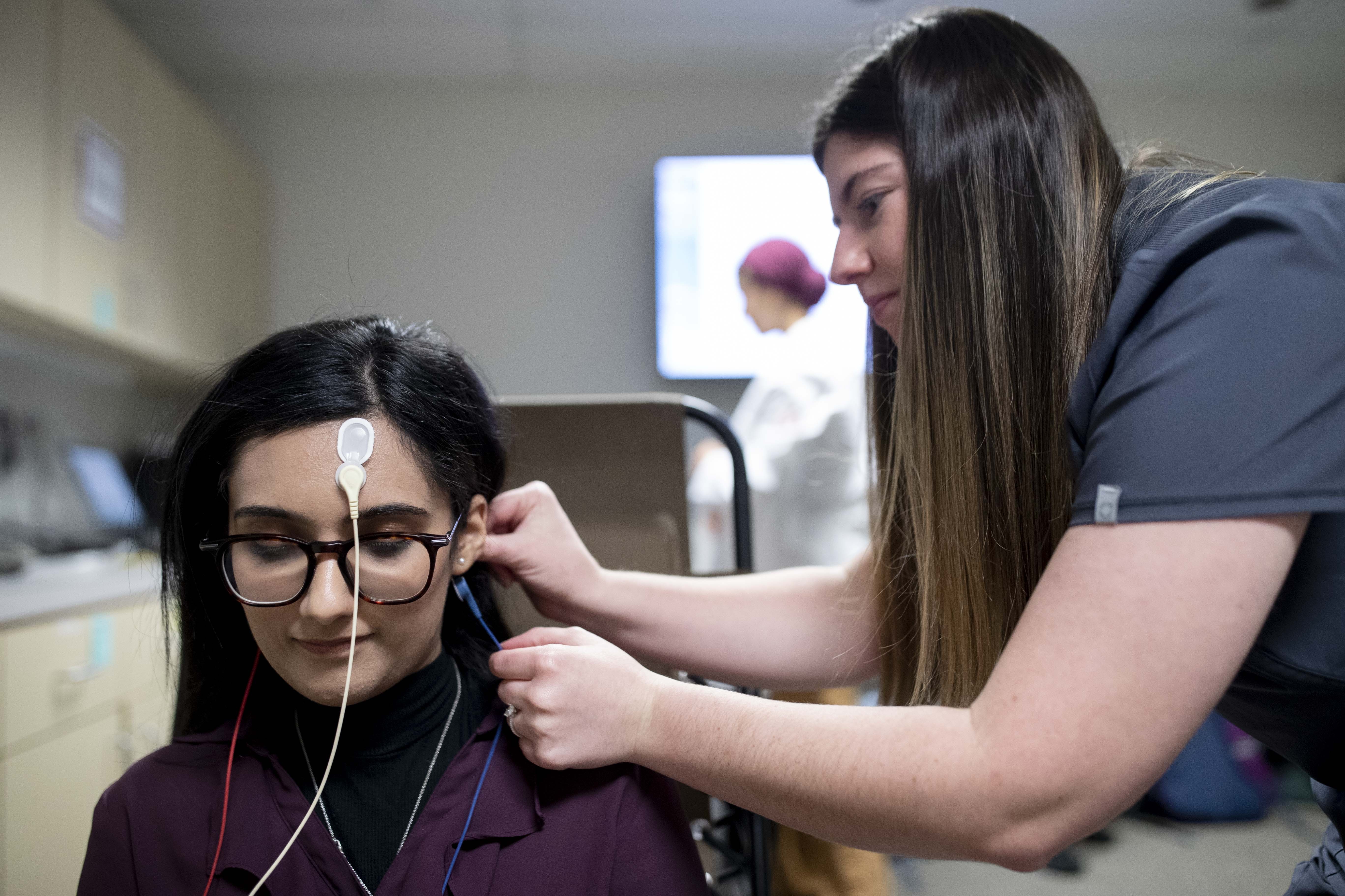Student in AUD lab examining patient