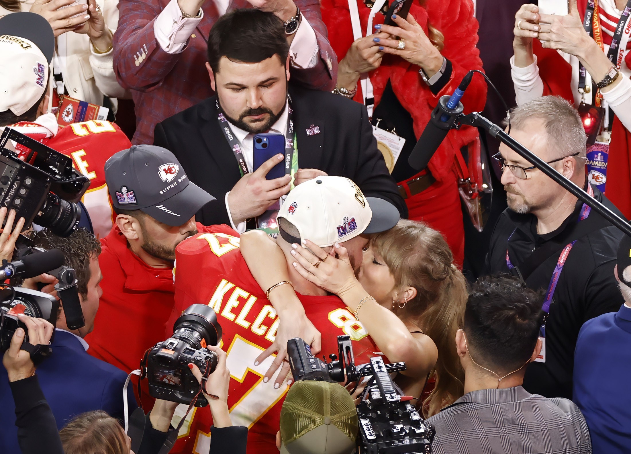 Taylor and Travis kissing on the field after the Super Bowl