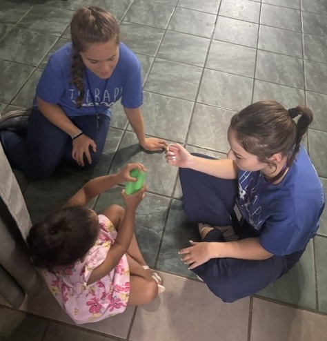 Two students sitting on the floor working with a young client