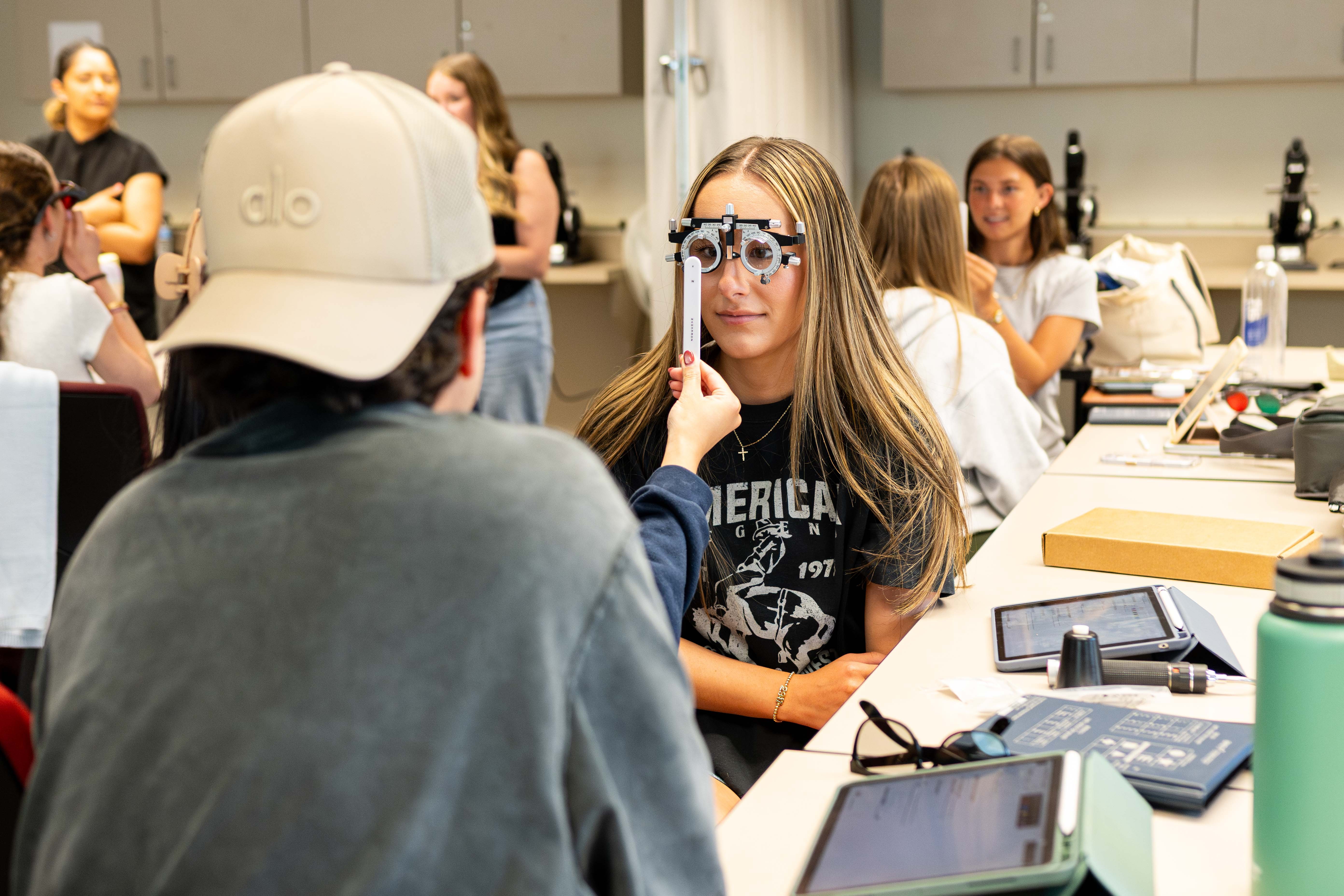 Students practice eye exams on each other in class