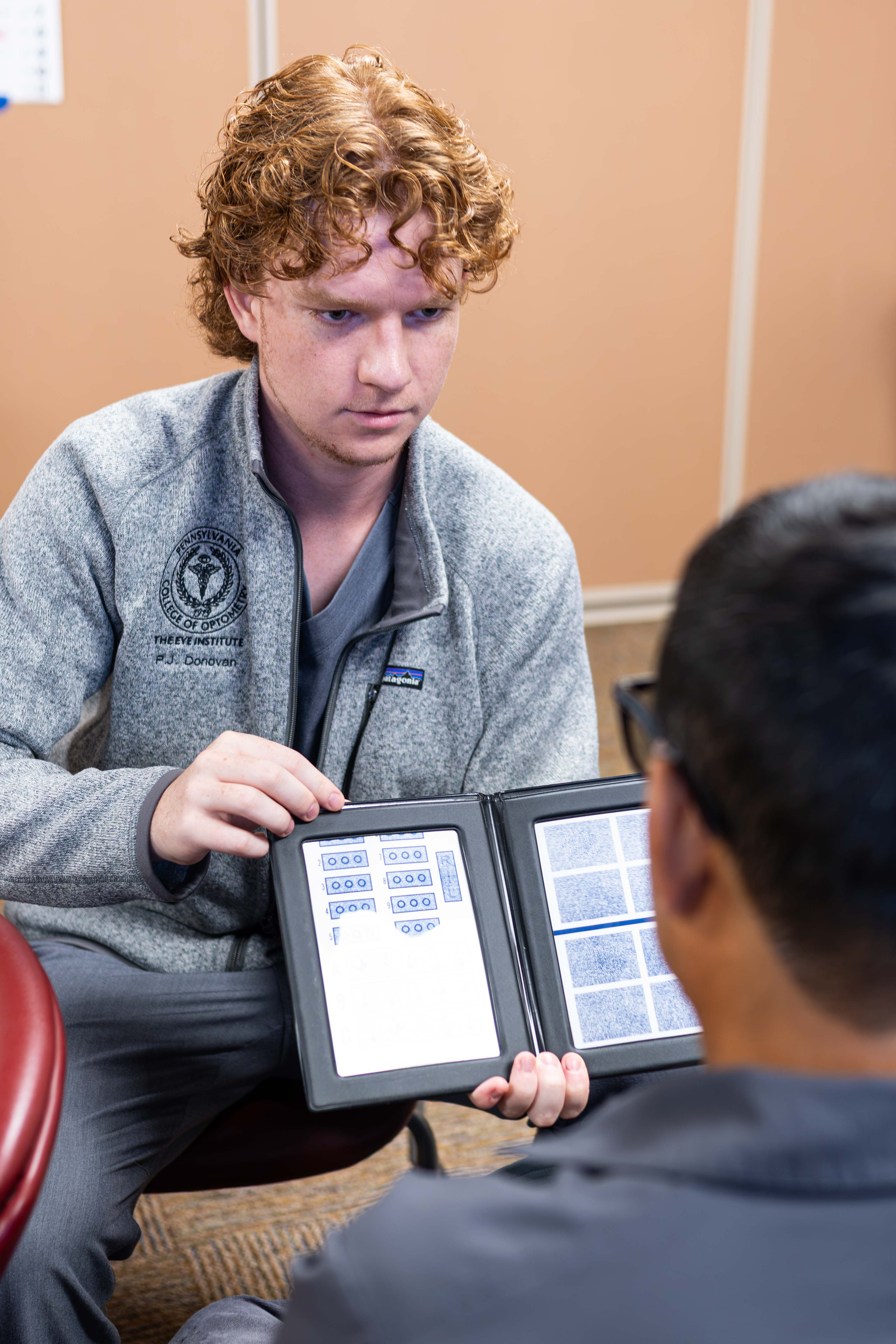 Student holds eye chart for patient