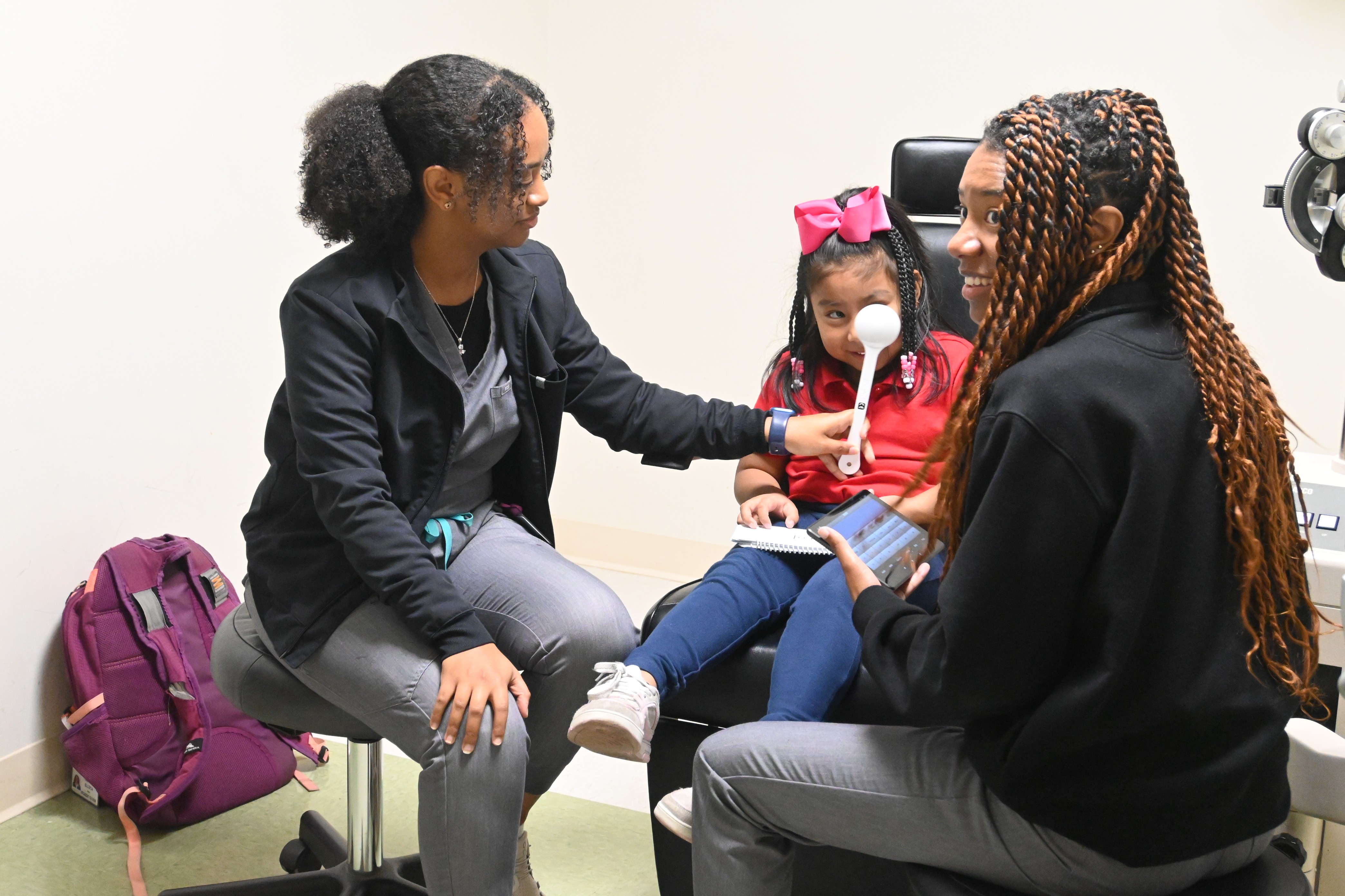 Two optometric interns examining a child 