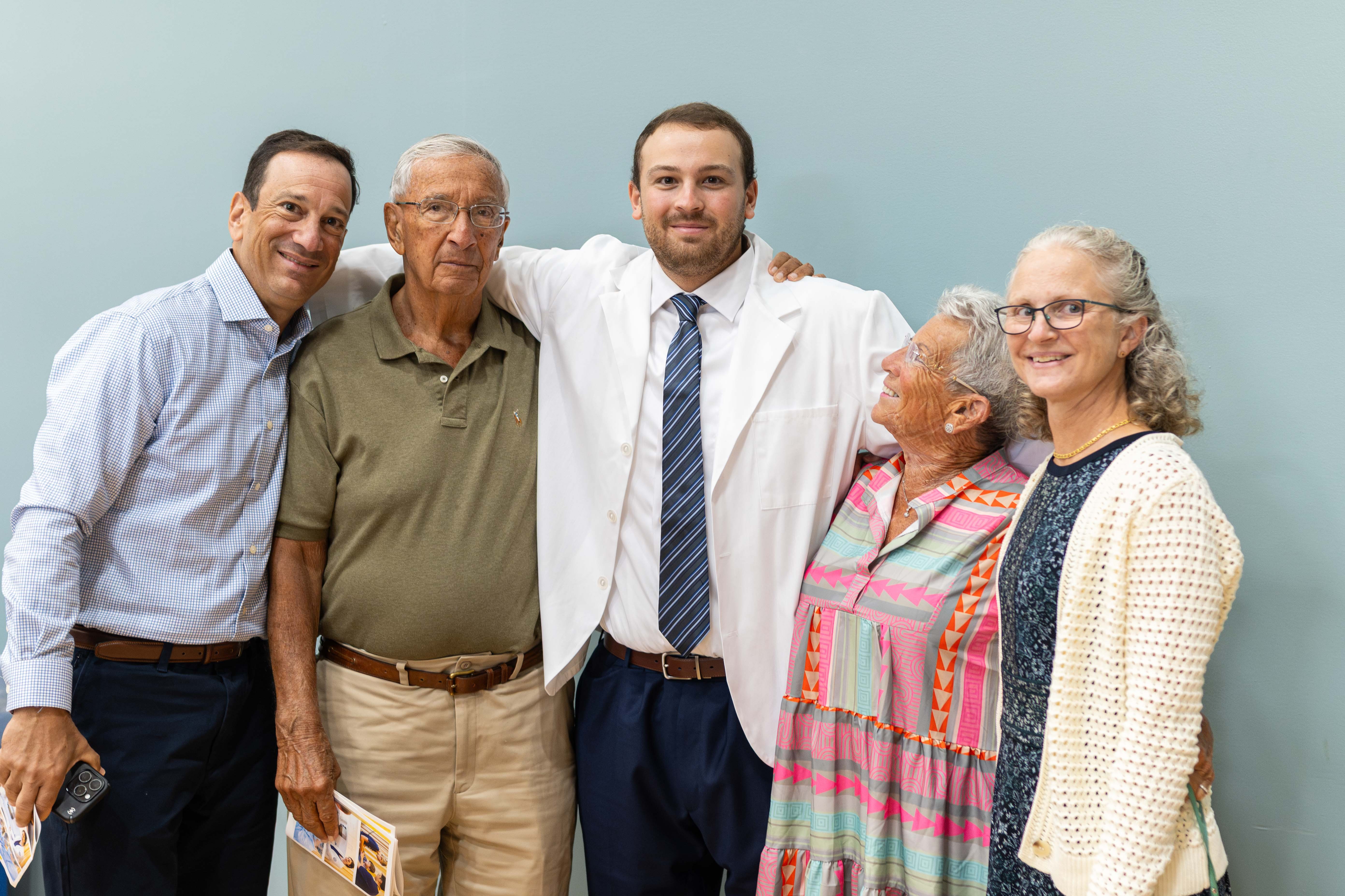 Happy family at white coat with their student