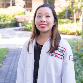 Victoria Wong smiling outside in a white coat
