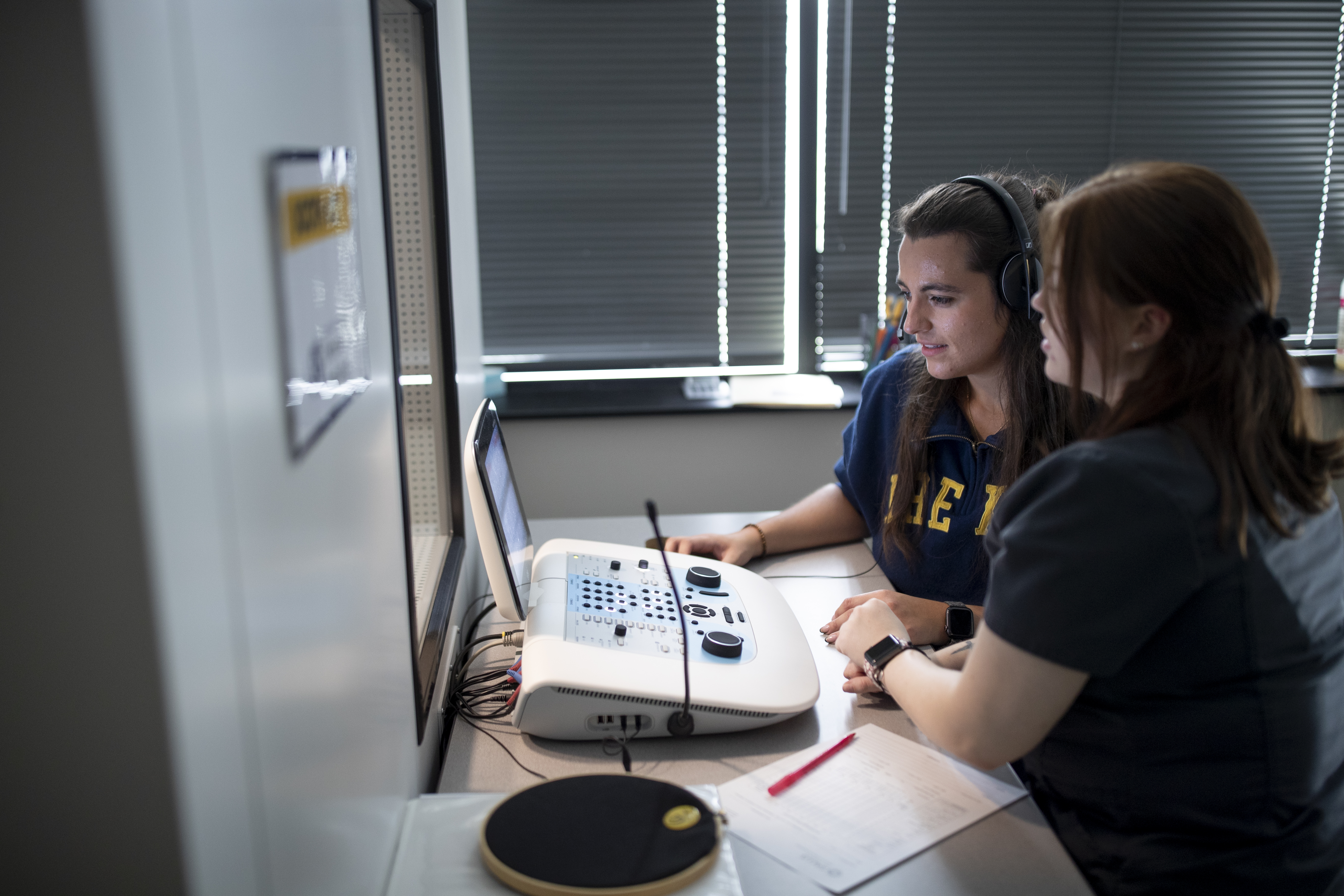audiology student sitting in front of booth