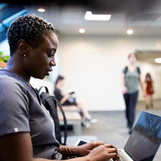 student typing on a laptop in the hallway