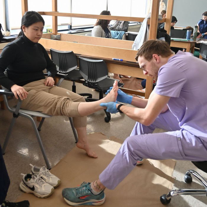 student examining a patient's foot