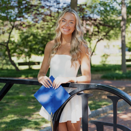 SLP student in white dress holding grad cap