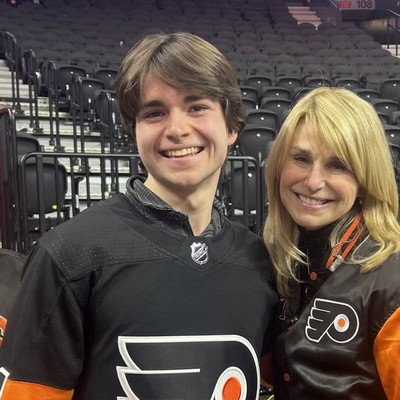 OT student wearing Flyers jersey, taking photo with singer