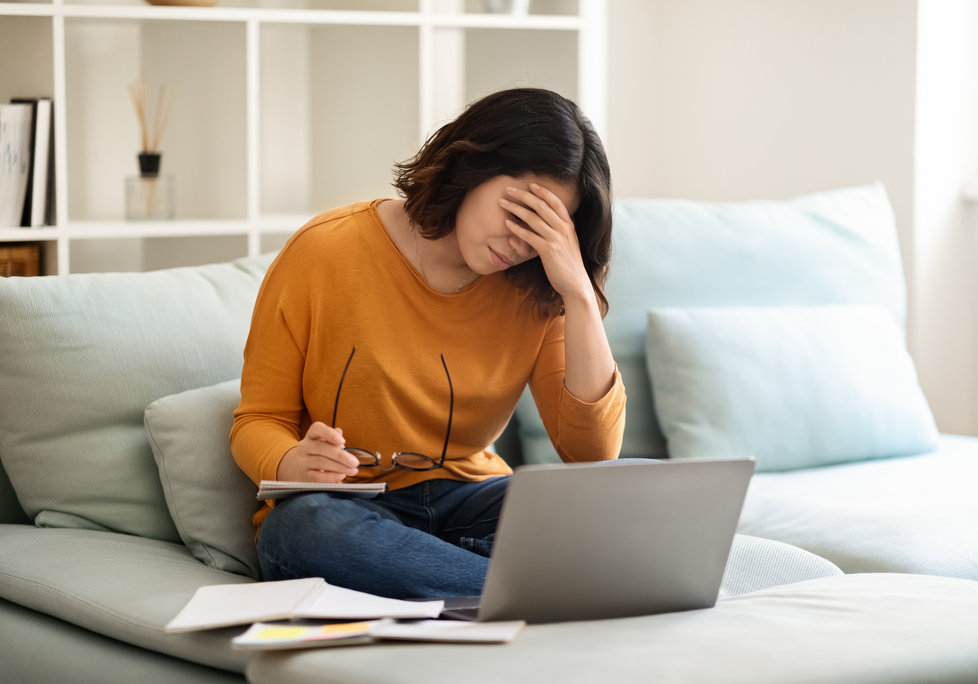 woman with her hand over her eyes, sitting at computer