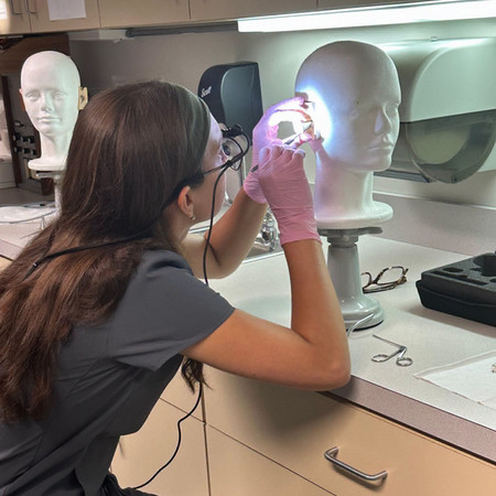 audiology student practicing ear wax removal on Carl head