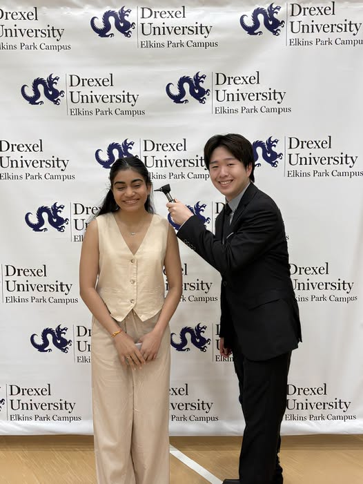 Jason holding an otoscope next to another student