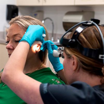 audiology student cleaning patient's ear