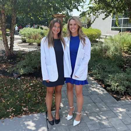 two PA students wearing their white coats