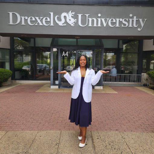 Jaylah in her white coat in front of the University