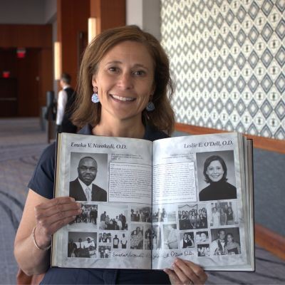 Alum holding a yearbook picture of herself thumpic