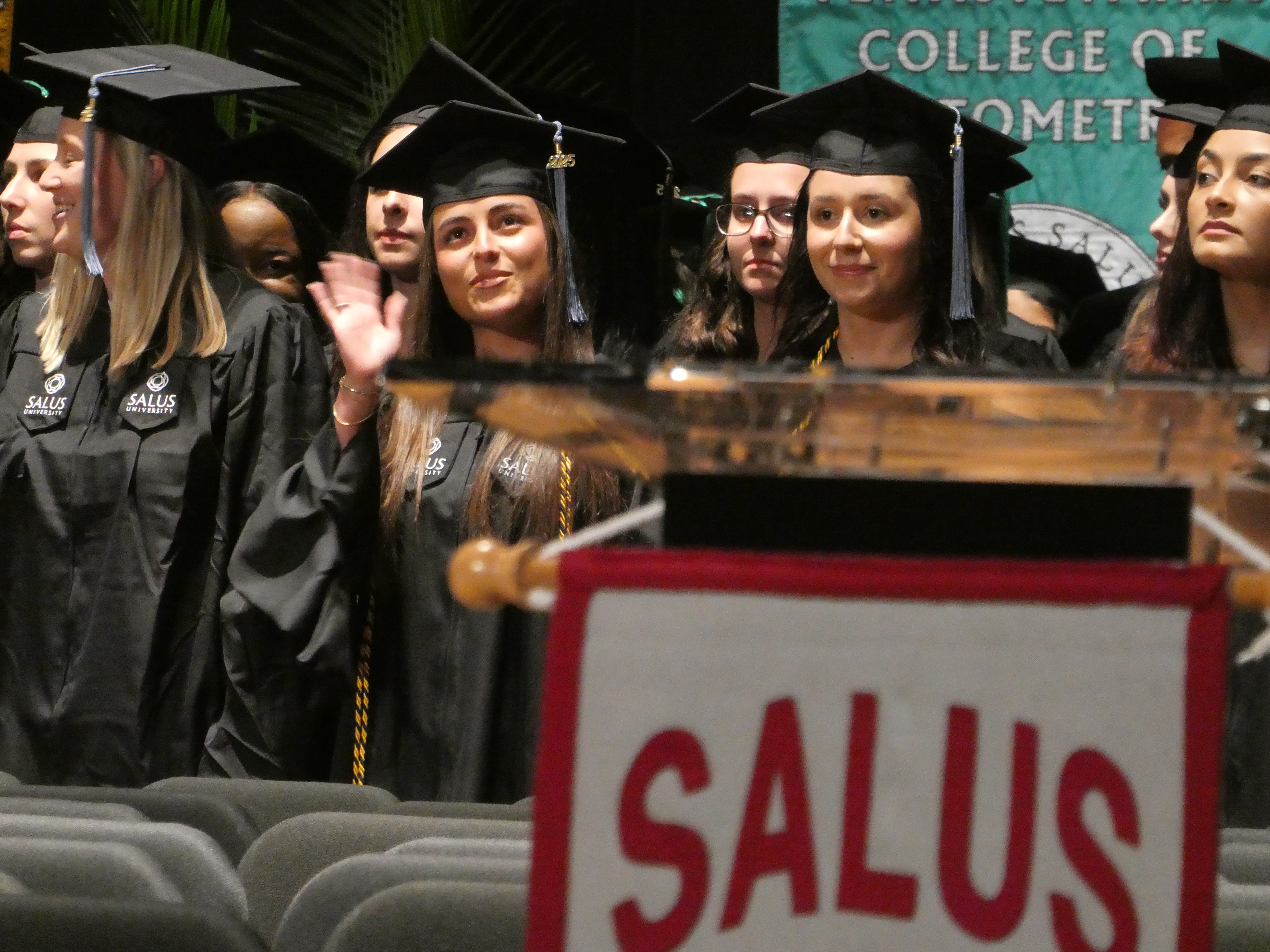 Graduate waving at family during commencement