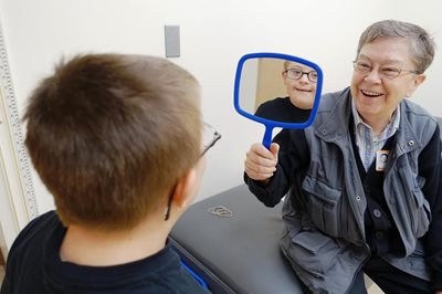 optometrist holding up mirror in front of child