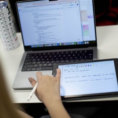 Student at computer and taking notes thumbpic