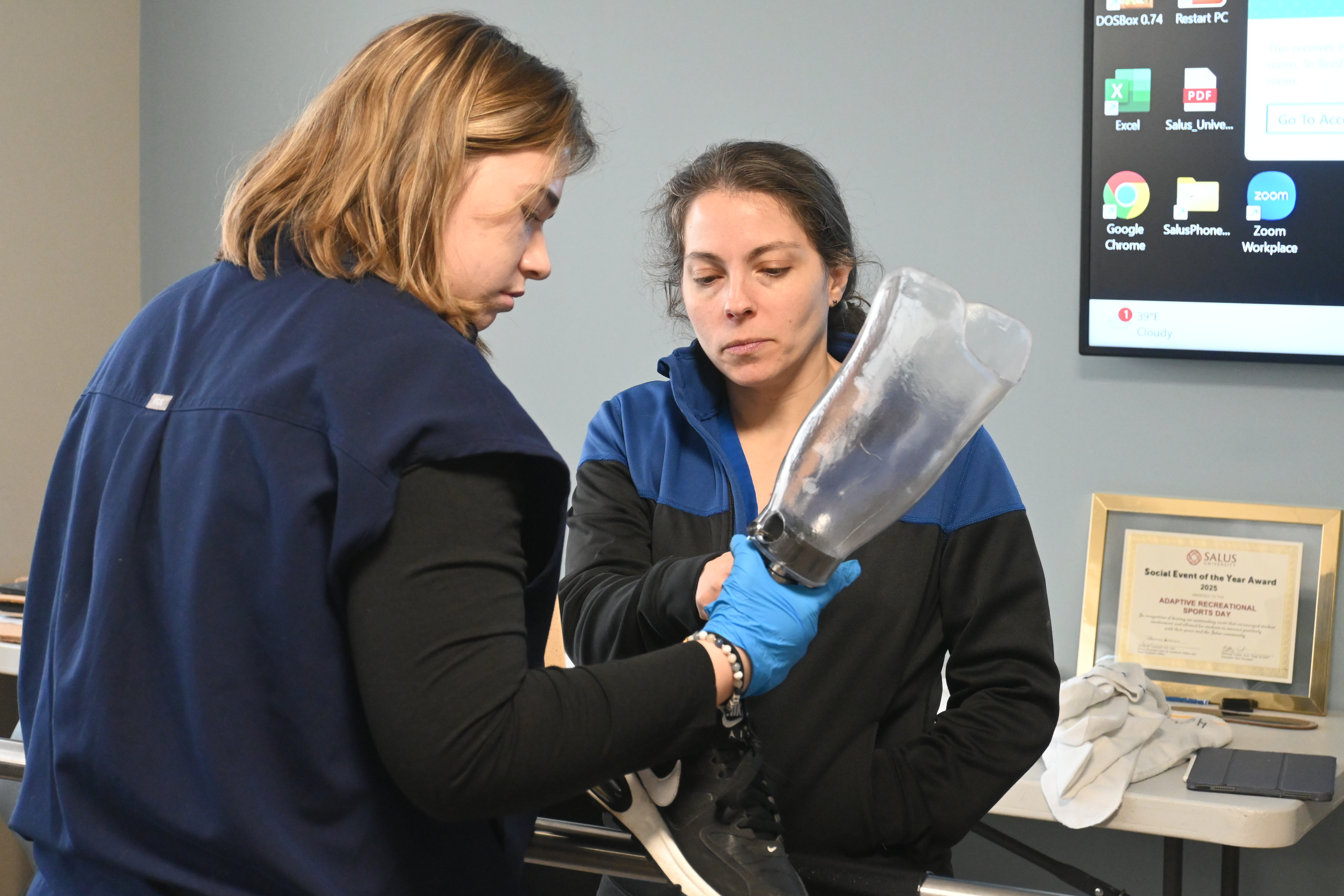 O&P student holding prosthetic while talking to professor