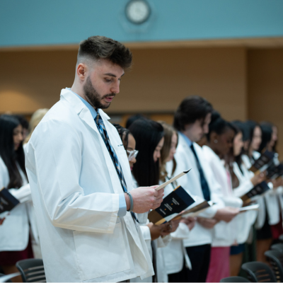 students in white coats reading oath