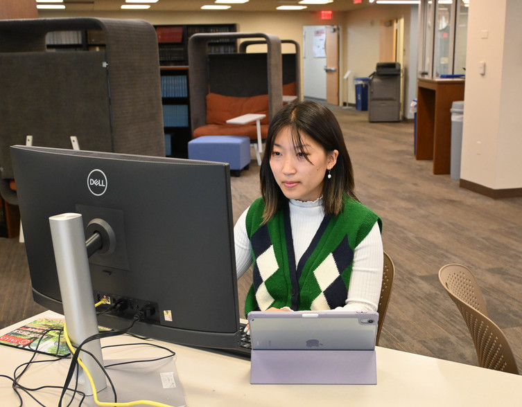 student staring at computer with iPad in front of her