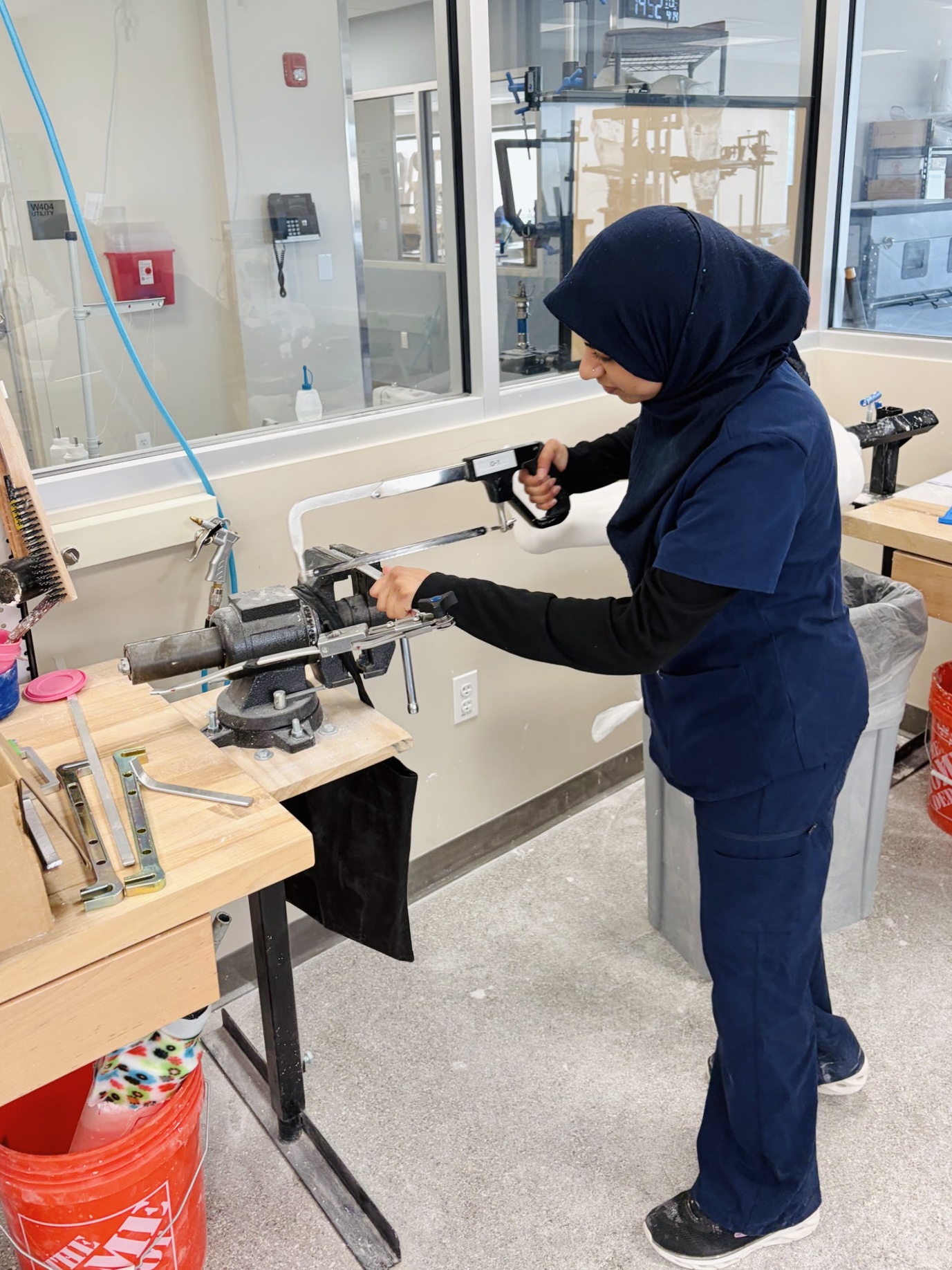 Syeda working in the O&P lab with a saw