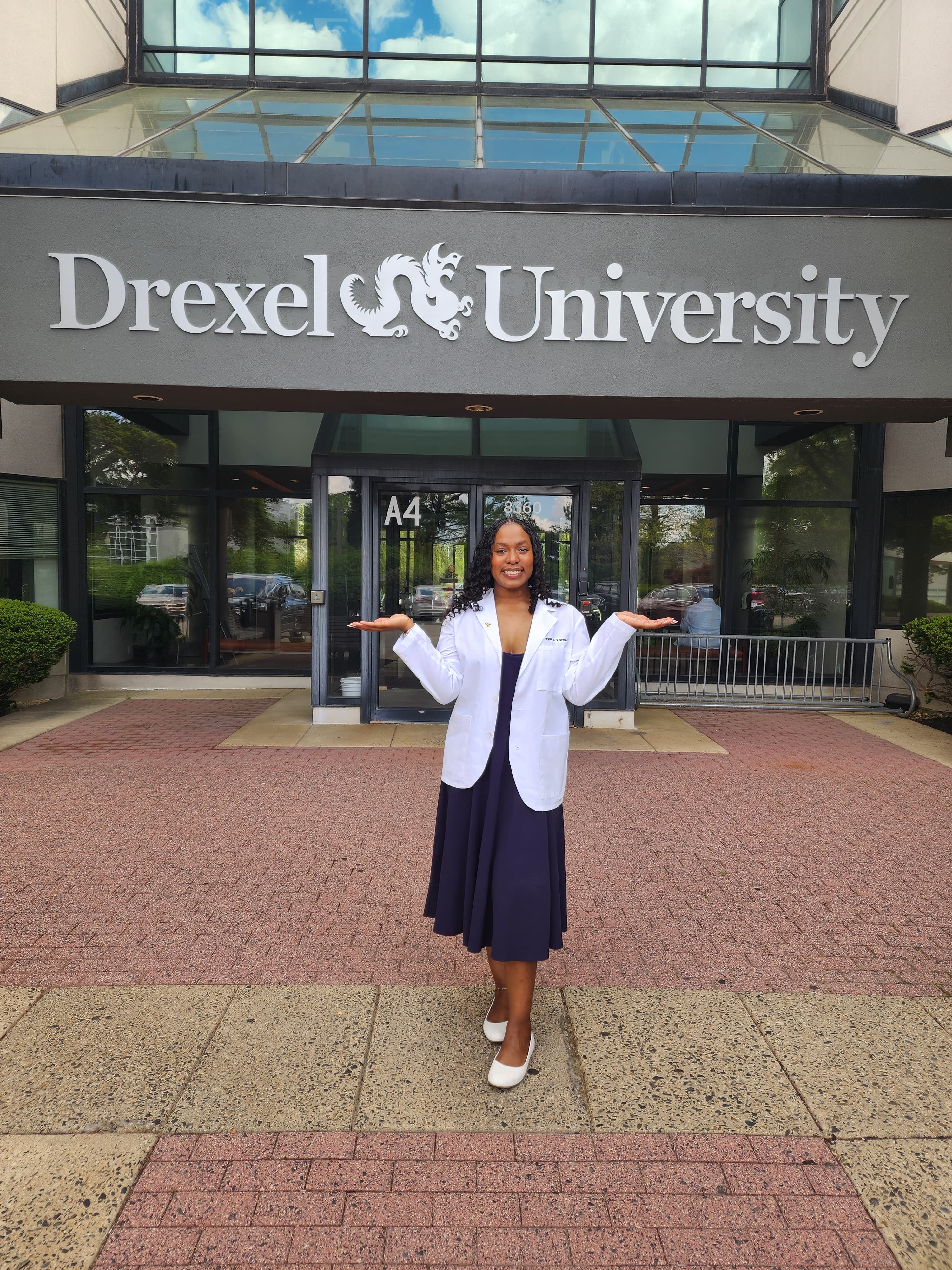 Jaylah wearing her white coat in front of the Drexel sign