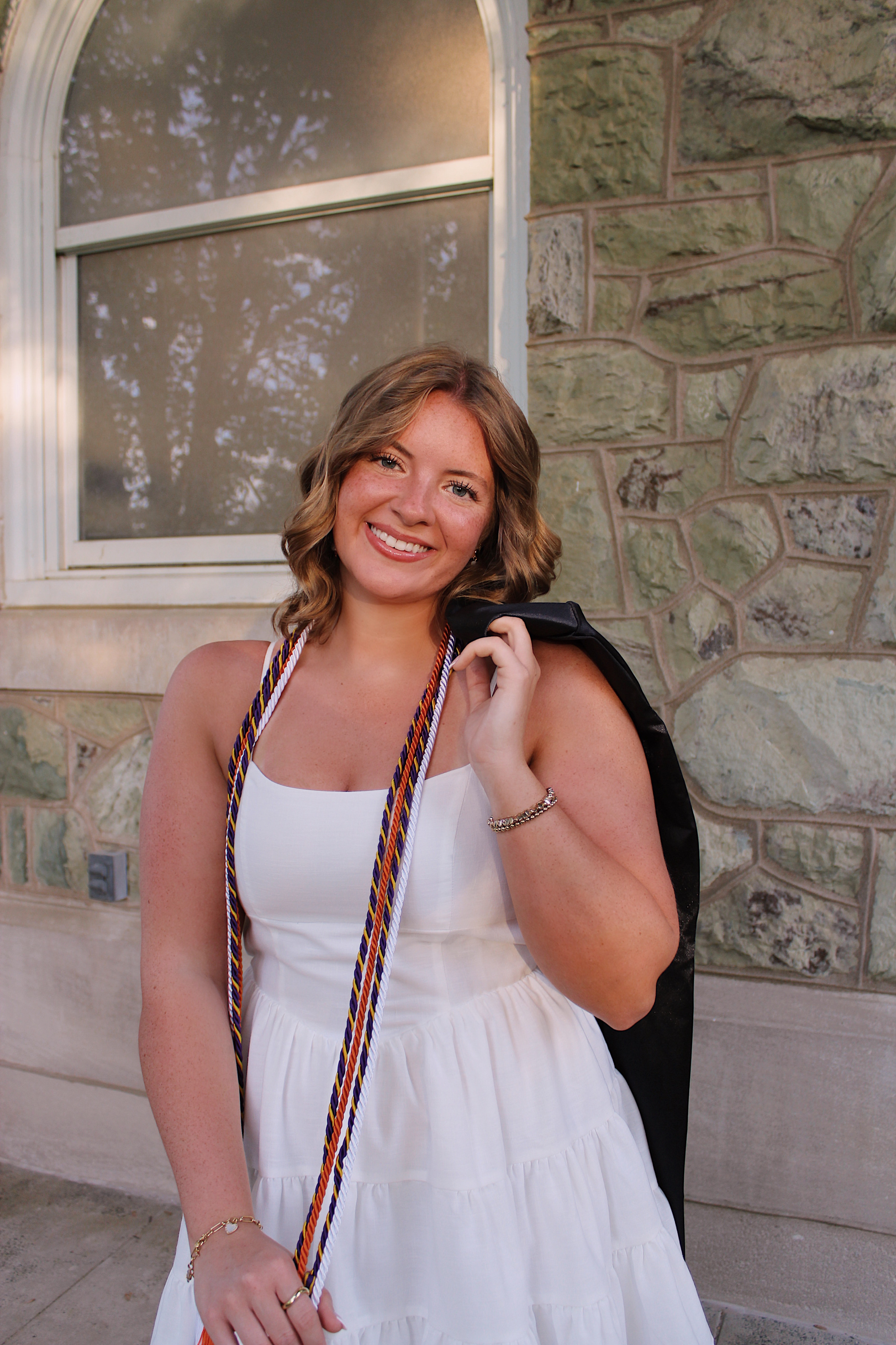 Cassidy wearing a white dress with grad gown