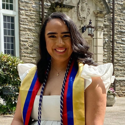 Ashley wearing a white dress with graduation cords