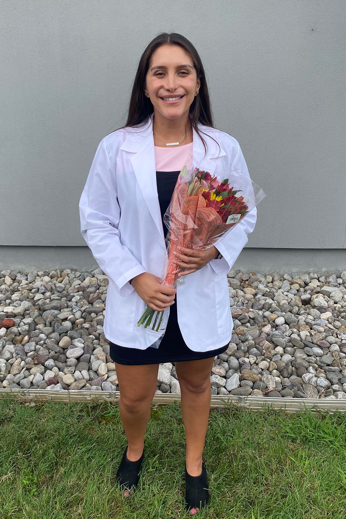 Veronica Baez holding flowers in her white coat