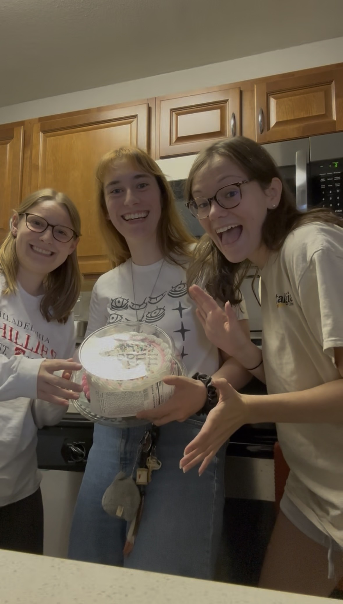 three girls holding a cake