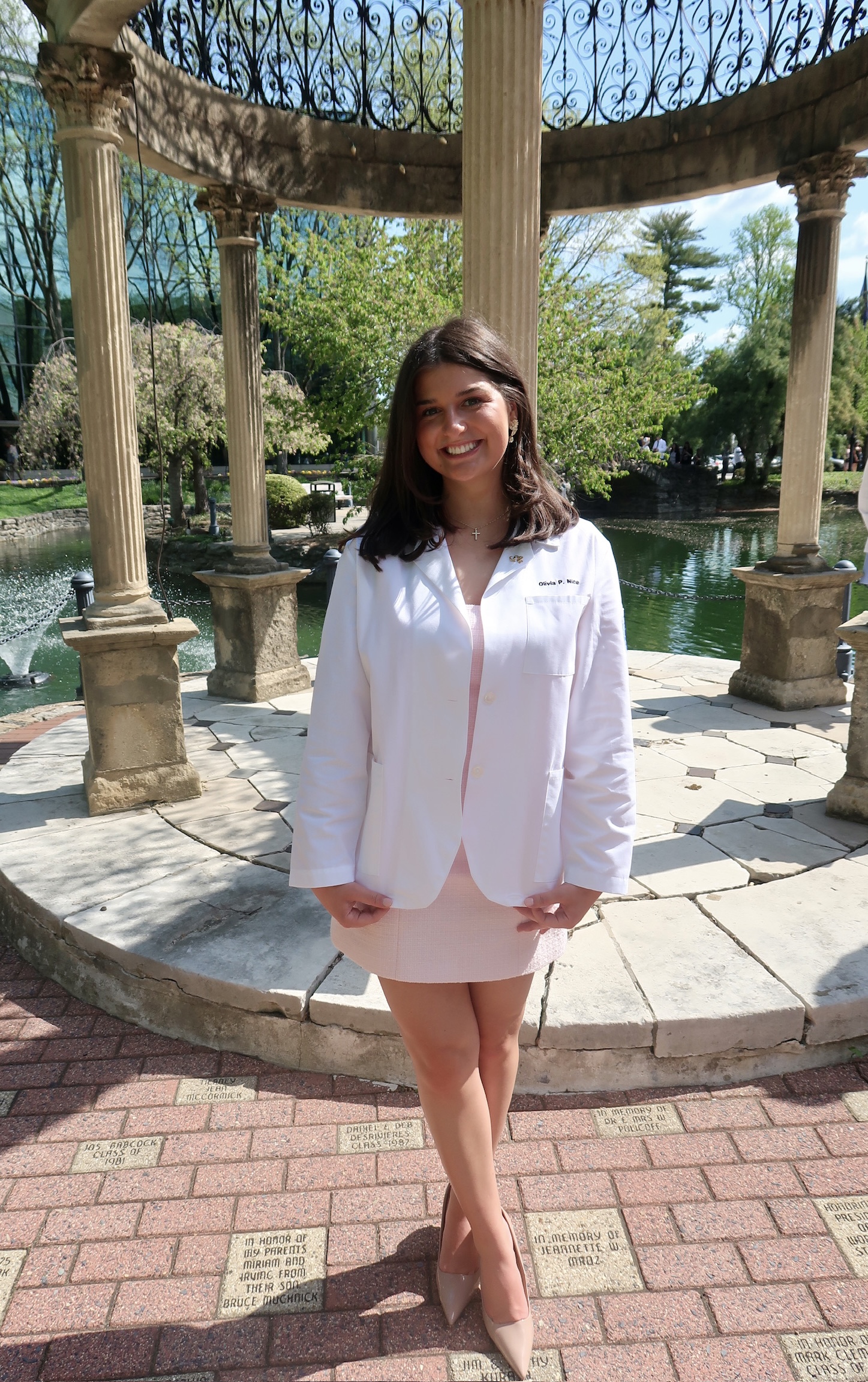 Olivia in her white coat in front of the gazebo
