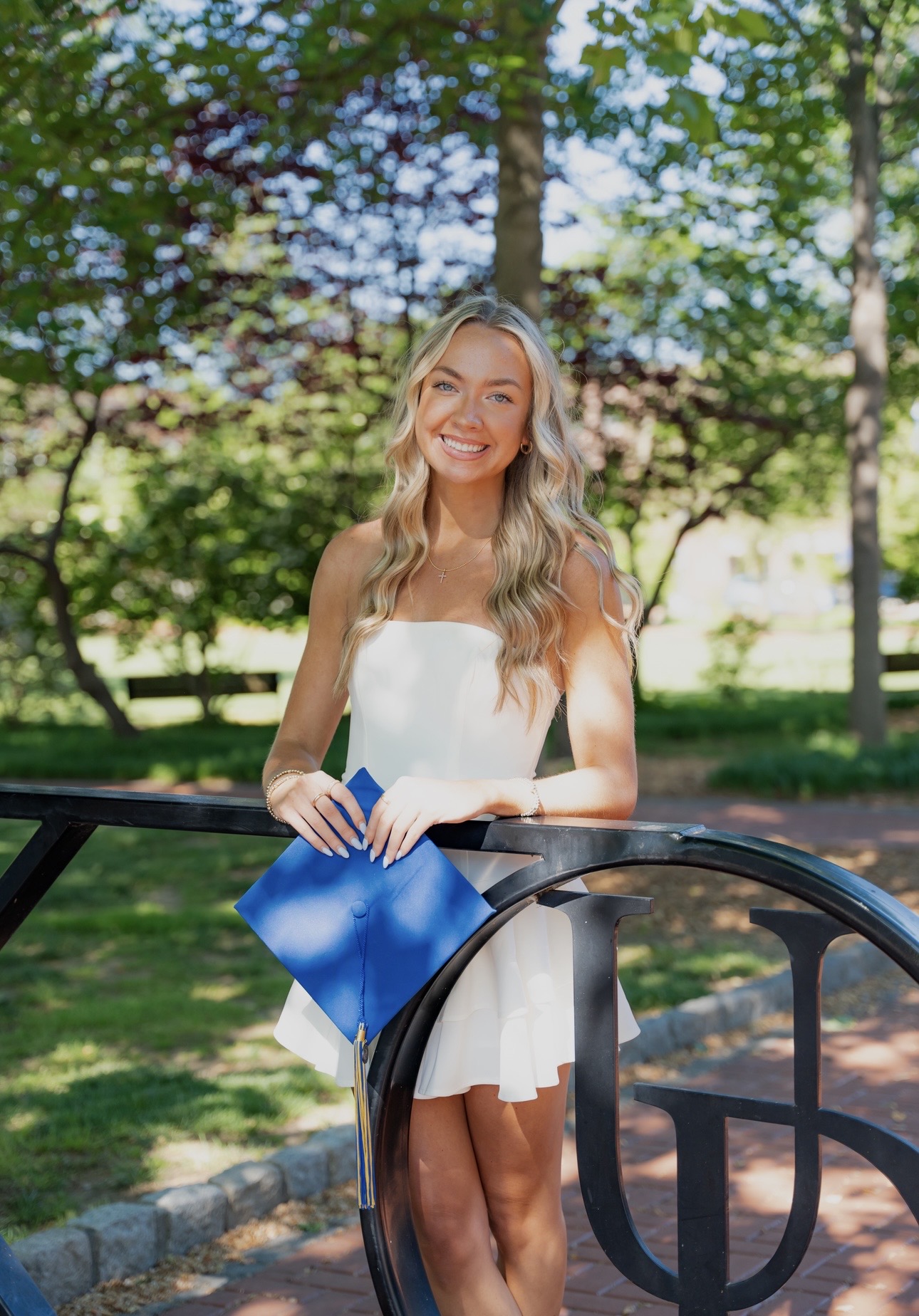 Madelyn wearing a white dress holding her grad cap