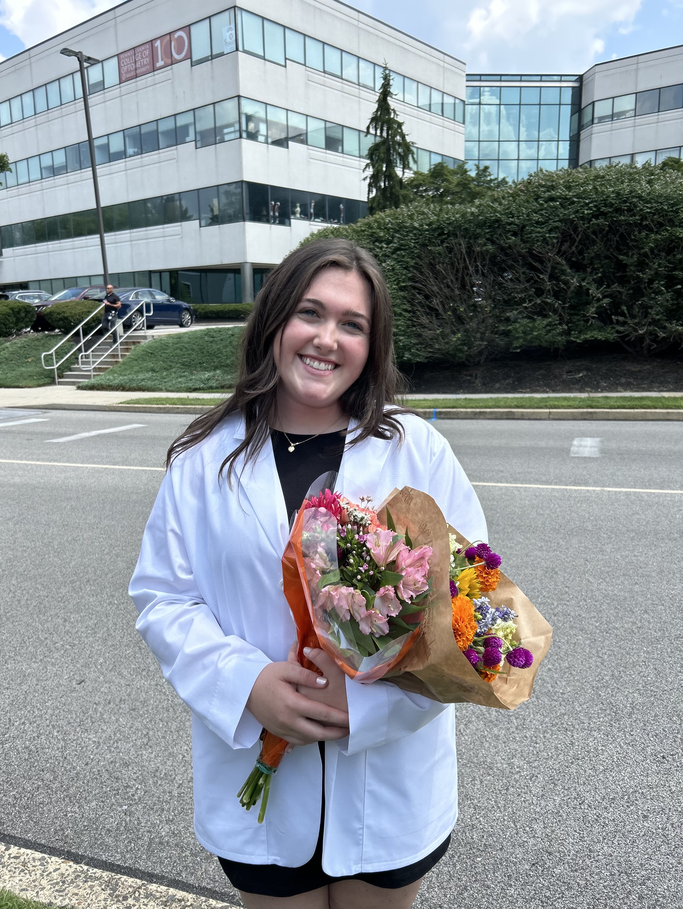 Megan in her white coat holding flowers