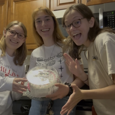 three girls holding a cake