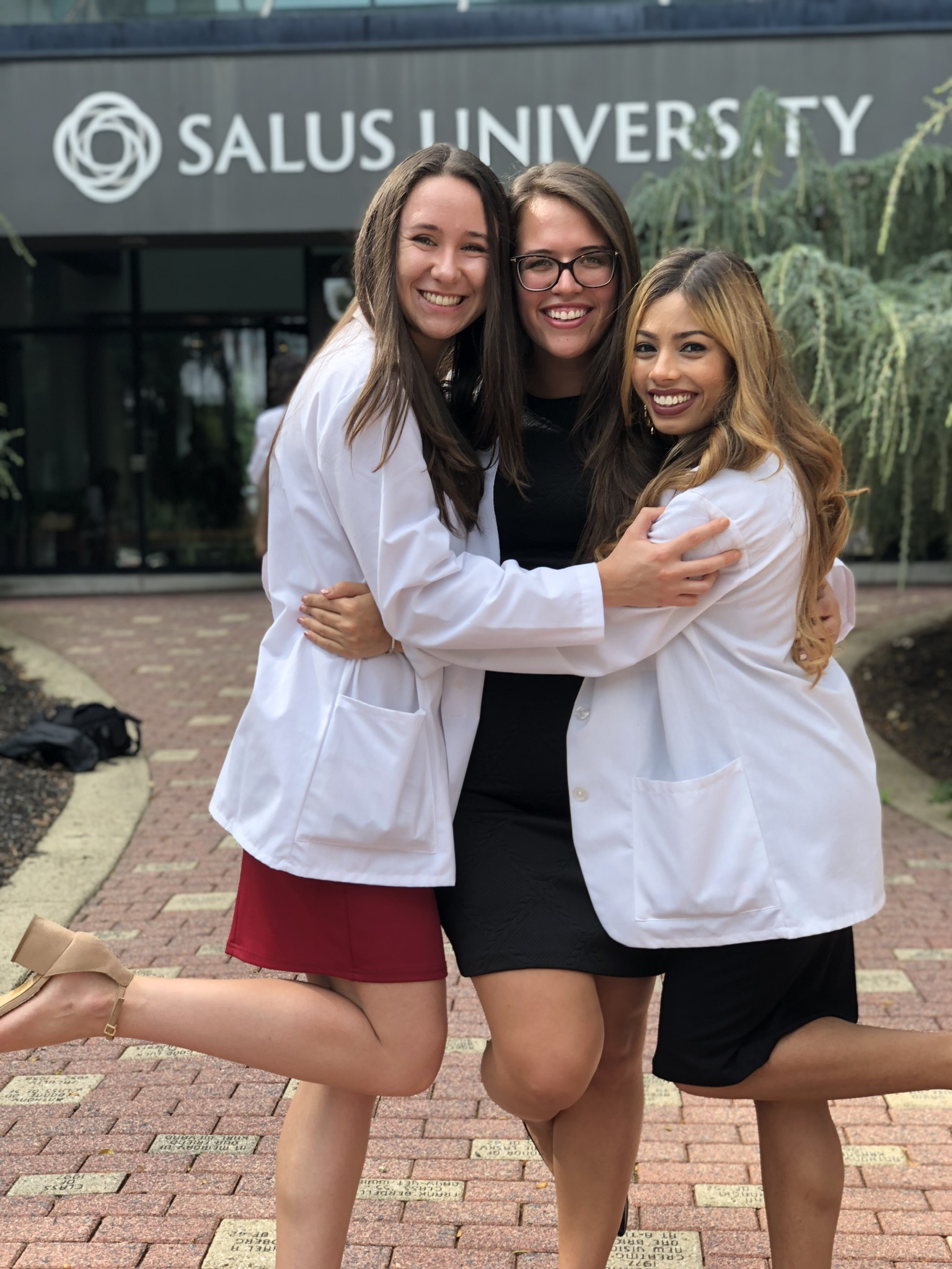 Samantha and her friends hugging outside the main entrance of Salus