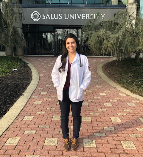 Samonne in a white coat outside the Salus main entrance